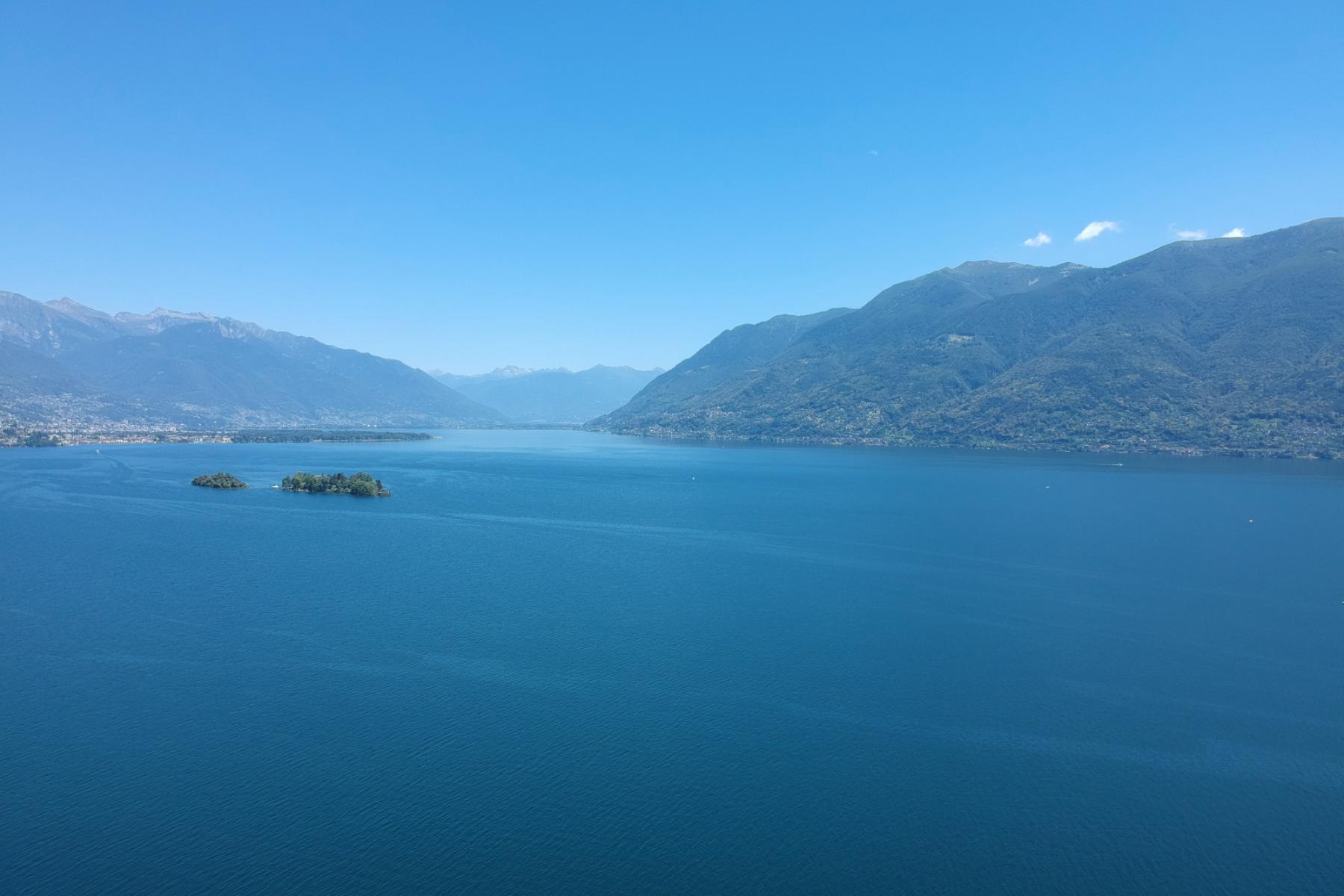 Der Ausblick auf den Lago Maggiore vom Ferienhaus Casa Ramerino aus ist absolut atemberaubend. Die Drohnen-Aufnahme zeigt den Blick nach Ascona, wobei die malerischen Brissago-Inseln im Mittelpunkt steht.