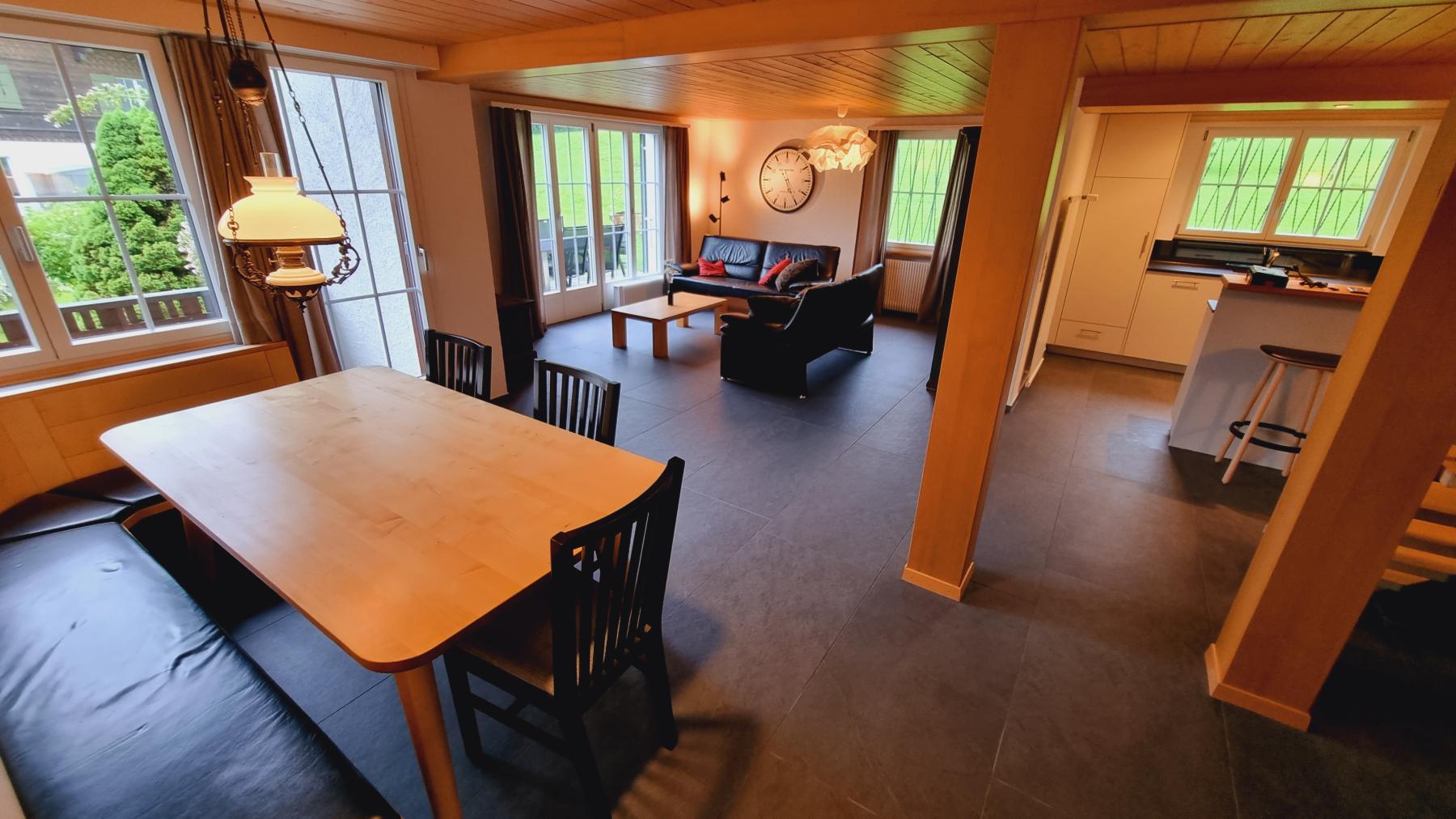 Das Wohnzimmer in unserem Chalet Catarina 1. Stock ist das Herzstück der Ferienwohnung. Hier befinden sich die Schaltzentrale für die Küche, einen grossen Esstisch und eine gemütliche Sitzgruppe. Das Bild zeigt das Wohnzimmer vom Eingang asus.