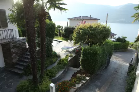Die Einfahrt zum Casa Ramerino von der Via Risaco 28 in Brissago ist einfach und verfügt zudem über eine Garage im unteren Teil des Ferienhauses. Bild Zeigt Einfahrt zum Casa Ramerino und Blick in den Garten mit Schwimmbad
