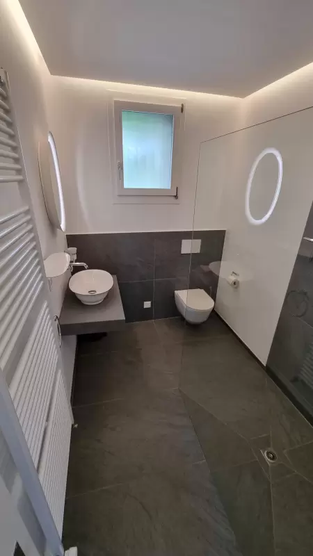 Eine grosszügige offene Dusche mit integriertem WC, verleiht Ihrem Badezimmer einen charmanten und natürlichen Stil. Das Bild zeigt das Badezimmer.