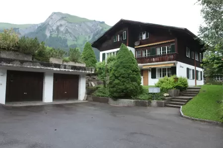 Das Chalet Catarina 1. Stock verfügt über einen geräumigen Parkplatz direkt vor dem Haus mit je einer abschliessbaren Garage pro Wohnung Das Bild zeigt den Vorplatz, im Hintergrund die Frontansicht des Chalet Catarina
