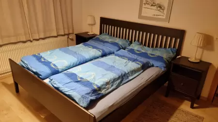 Gemütliches Schlafzimmer im Chalet Catarina 1. Stock verfügt über zwei komfortable Betten, die für eine erholsame Nacht sorgen. Das Bild zeigt das Schlafzimmer mit den 2 Betten. Das Bettgestell ist braun und die Duvets sind blau angezogen.