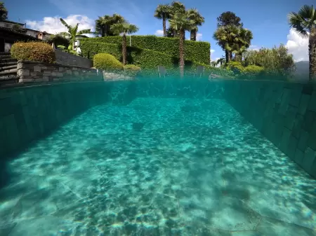 Dank des verwendeten Gottardgranits scheint das Wasser im Pool, Schwimmbad glasklar und türkisfarben zu schimmern. Das Bild wurde mit einer goPro aufgenommen und zeigt die hälfte Unterwasser und ausser dem Wasser