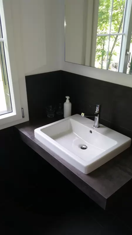 Die stilvolle Dusche mit integriertem WC ist eine perfekte Ergänzung zur charmanten Ferienwohnung. Das Bild zeigt den Ausschnitt vom Waschtisch mit beleuchtetem Spiegel.