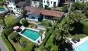 Die Drohnen-Luftaufnahme des Ferienhauses Casa Ramerino in Brissago zeigt ein beeindruckendes Bild. Das Schwimmbad fügt sich perfekt in die Umgebung ein.