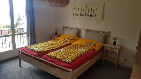 Die modernen Möbel verleihen dem Zimmer eine elegante Ästhetik. Bequeme Stühle und ein kleiner Salontisch laden zum Entspannen und Geniessen der Aussicht ein. Das Bild zeigt das Doppelzimmer mit der Türe auf den Balkonm welche geöffnet ist