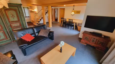 das grosse offene Wohnzimmer mit dem Esstisch und der Eckbank im Chalet Catarina an der Lenk perfekt für gemütliche Stunden mit der Familie oder Freunden. Das Bild zeigt den Esstisch und das grosse offene Wohnzimmer.